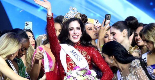 Fatima Bosch raising her hand in joy after being crowned Miss Universe 2025, surrounded by contestants celebrating on stage.