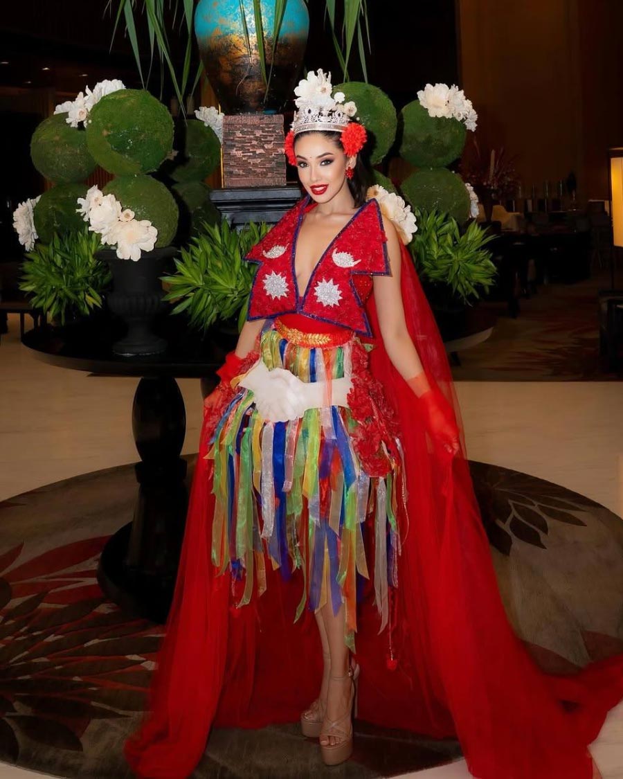 Sanya Adhikari wearing Nepal’s colorful national costume with red accents and floral headpiece, designed by Aviad Arik Herman for Miss Universe 2025.