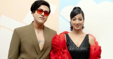 Riyan Giri wearing red sunglasses and a blazer stands beside debut actress Pratima Thapa in a black dress with red sleeves, posing at a film announcement event.