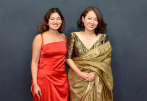 Shape of Momo actress Gaumaya Gurung in a red dress stands beside director Tribeny Rai in a gold sari.