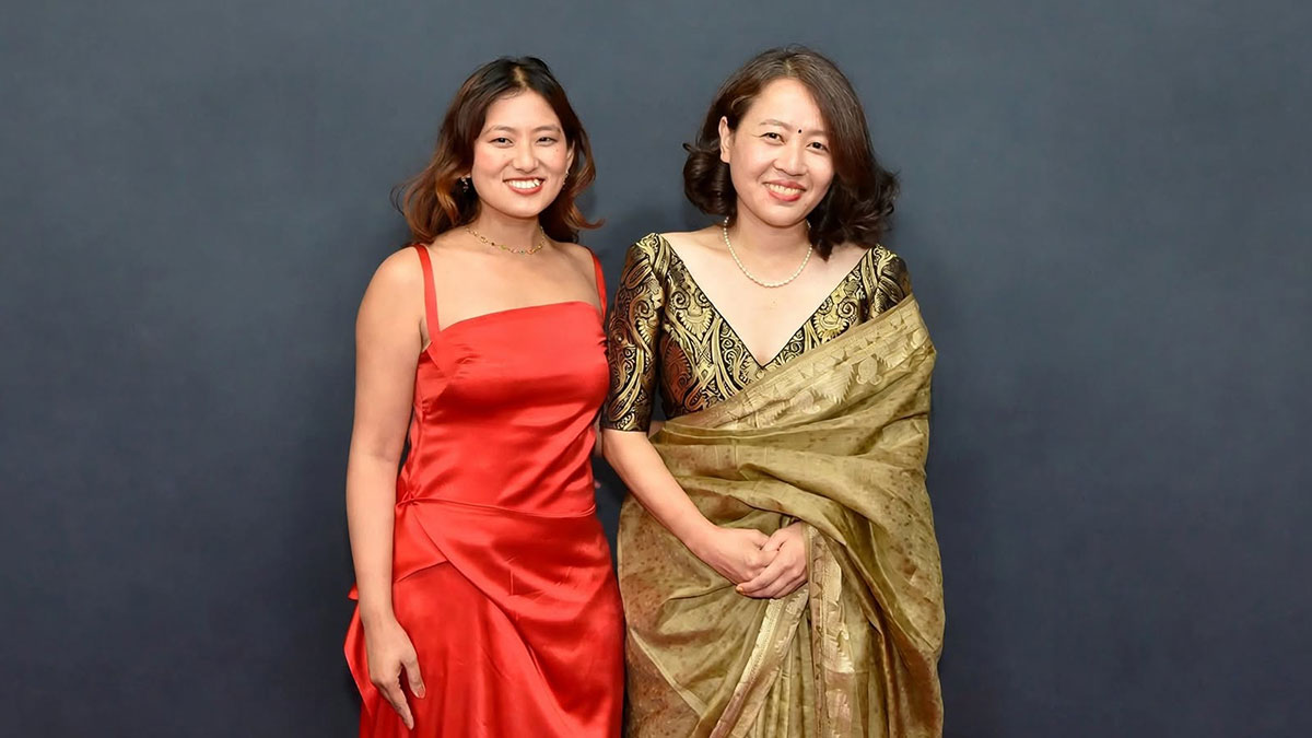 Shape of Momo actress Gaumaya Gurung in a red dress stands beside director Tribeny Rai in a gold sari.