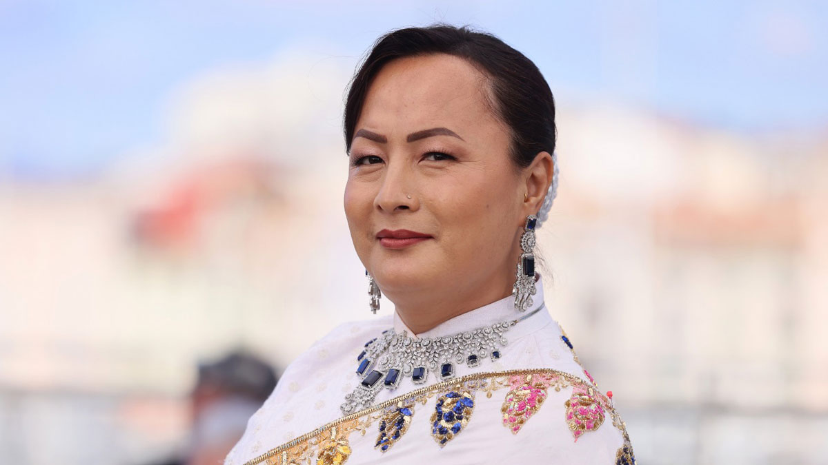 Pushpa Thing Lama wearing a white outfit with colourful embroidery, a blue-stone necklace and matching earrings.