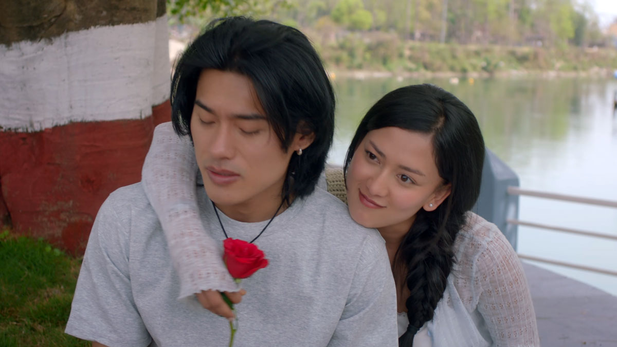 Upasana Singh Thakuri hugs Sonam Topden from behind while holding a red rose beside a lake in the Jalaaki trailer.